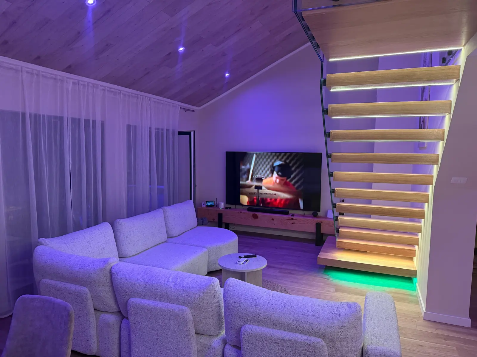 Smart-TV neben der beleuchteten Treppe im Wohnzimmer